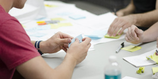 Personen sitzen am Tisch und machen Gruppenarbeit