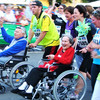 Ein Marathon. Es sind laufende Menschen und Menschen in Rollstühlen zu sehen.