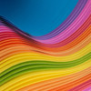 The abstract image consists of thin fabrics layered on top of each other. They form a wave with a colorful gradient of blue at the upper left and lower right edge over pink, red, orange, yellow and green in the center of the picture.