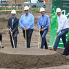 Six people are standing with spades in their hands behind a small pile of heaped up earth.