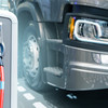 A gray truck stands next to an electric charging pole with an electric car charging cable plugged into it.