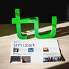 The February 2023 issue of unizet is on the floor. Behind it are the two letters t and u.