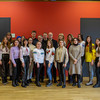 Several people are standing in front of a red wall.