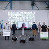 Group picture with several people, in the background a screen with participants of video chats