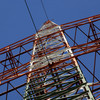 A power pole from below with blue sky in the background.