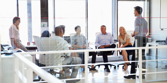 six people sitting together in a bright room are facing each other